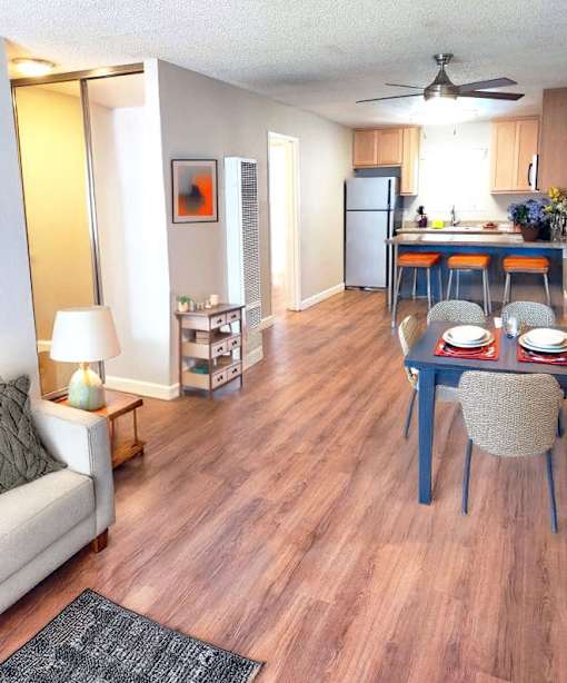 A living room with a couch, a table with chairs, and a kitchen area in the background.