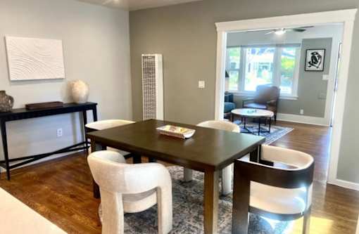 A dining room with a dark wooden table and white chairs.