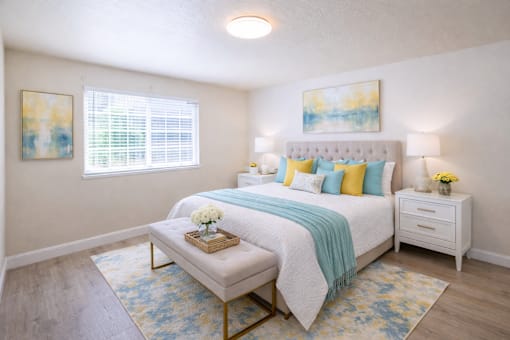 A bedroom with a white bed and a blue and yellow throw blanket.