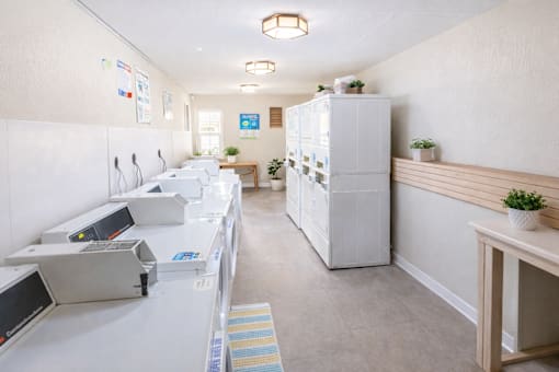 A white refrigerator is in the middle of a room with a white counter.