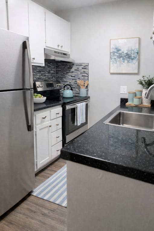 A modern kitchen with a black countertop and stainless steel appliances.