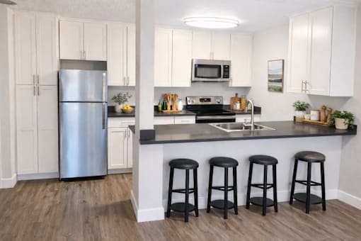 A kitchen with white cabinets and a stainless steel refrigerator.