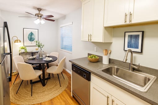 A kitchen with a table and chairs and a fridge.