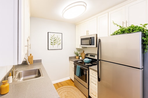 A small kitchen with a refrigerator, sink, and stove.
