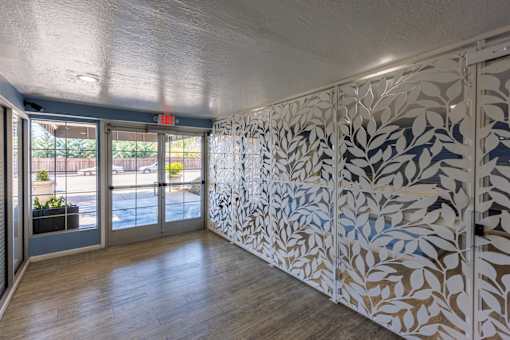 A hallway with a wall of leaves and a red exit sign.