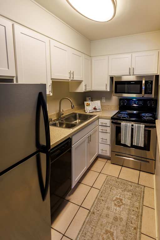 A kitchen with a black fridge, stove, and microwave.