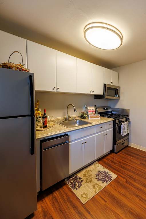 A kitchen with a refrigerator, microwave, and oven.