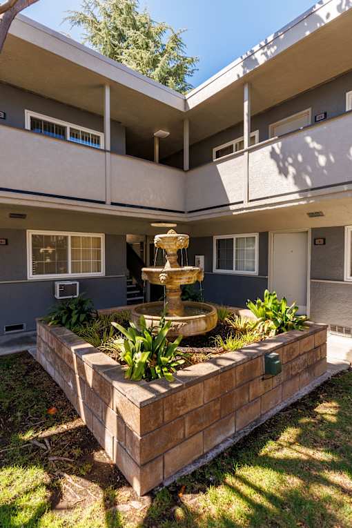 A courtyard with a fountain and a wall.