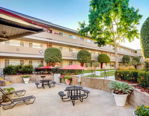 A courtyard with tables and chairs is surrounded by a building.