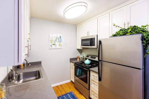 A small kitchen with a refrigerator, sink, and stove.