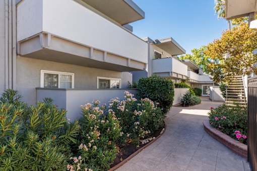 A white building with a garden in front.