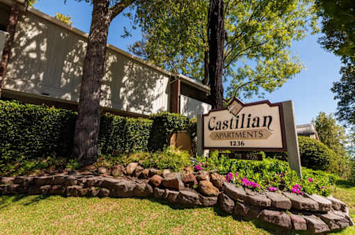 A sign for Castilian Apartments is in front of a building.