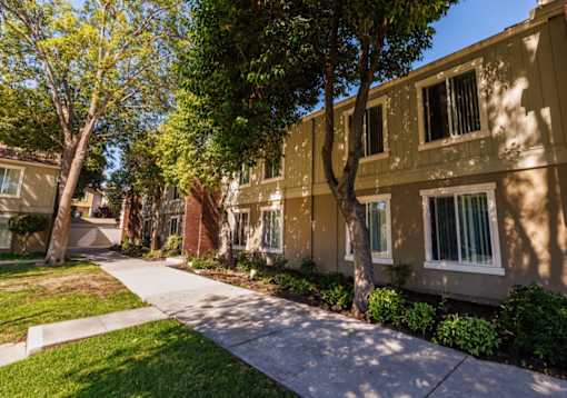 A row of apartment buildings with trees in front.
