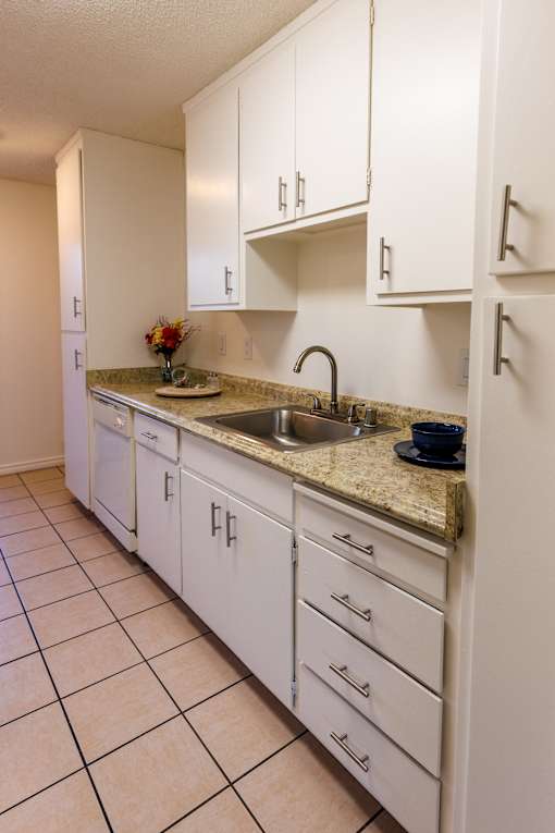 A kitchen with white cabinets and a granite countertop.