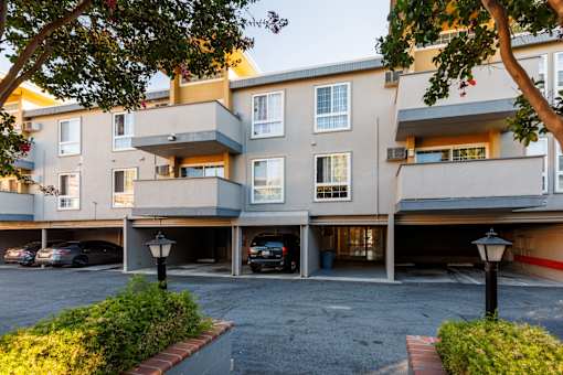 A parking garage in front of a multi-story apartment building.