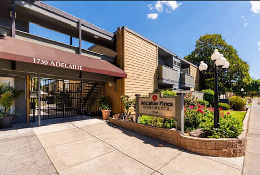 The front of the Melalade Fines Apartments building is shown with a clear blue sky in the background.