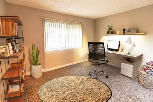 A room with a desk, chair, and a window with blinds.