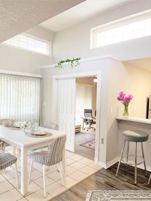 A dining room with a table set for two and a bar area with a stool.