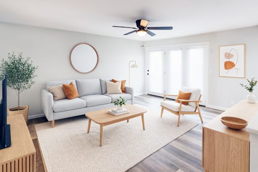 A living room with a grey couch, a wooden coffee table, and a ceiling fan.