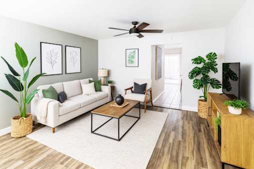 A living room with a white couch, a wooden coffee table, and a ceiling fan.