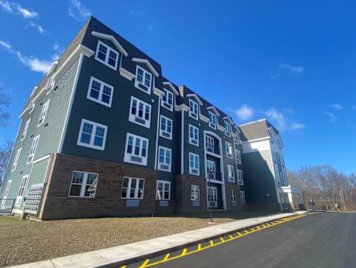 A large apartment building with a parking lot in front.