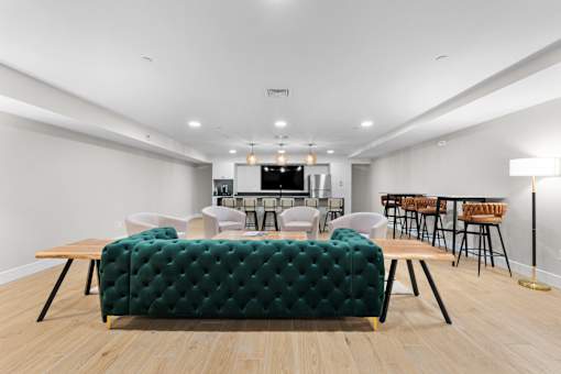 A room with a green tufted sofa and wooden floors.