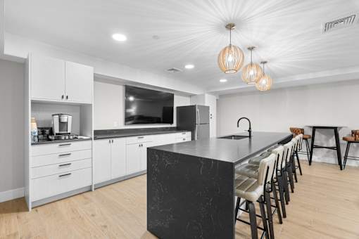 A modern kitchen with a black marble island and wooden floors.