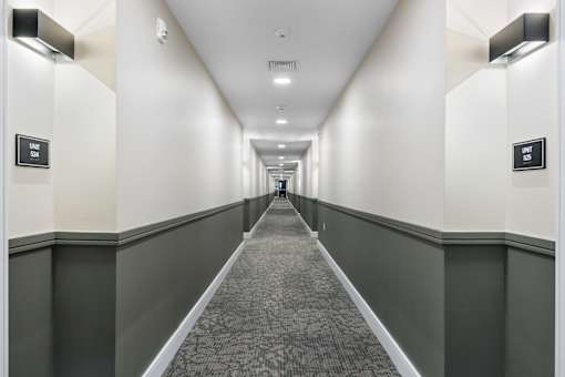 A long hallway with a carpeted floor and white walls.