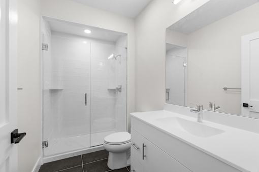 A white bathroom with a toilet, sink, and shower.