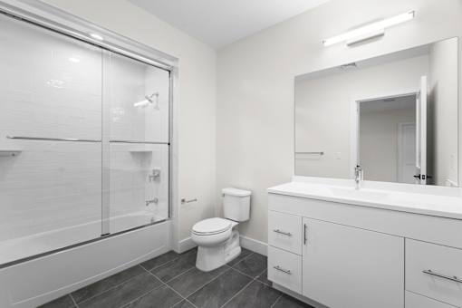 A white bathroom with a toilet, sink, and shower.