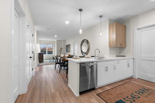 A modern kitchen with white cabinets and a wooden floor.