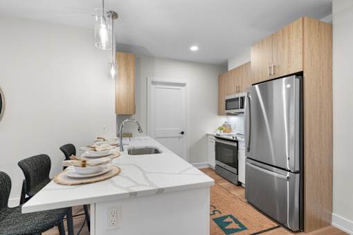 A kitchen with a white counter top and a refrigerator.