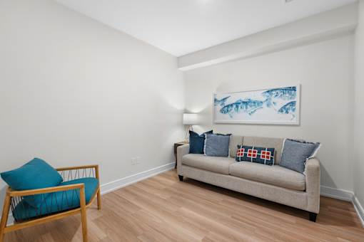 A living room with a couch, chair, and a painting of fish.