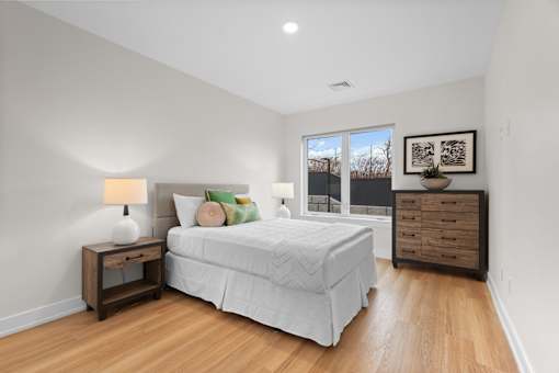A bedroom with a bed, nightstand, and a painting on the wall.
