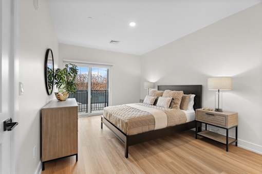 A bedroom with a large bed, a wooden nightstand, and a plant on a cabinet.