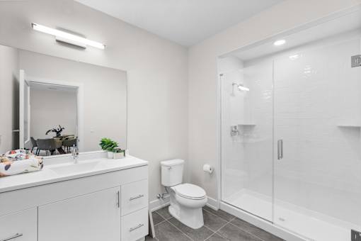 A white bathroom with a toilet, sink, and mirror.