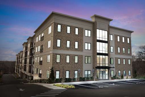 A modern apartment building with a parking lot in front.