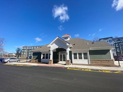 A building with a white front and a red roof is in front of a blue sky.