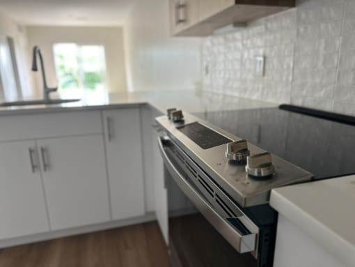 a white kitchen with a stove and white cabinets