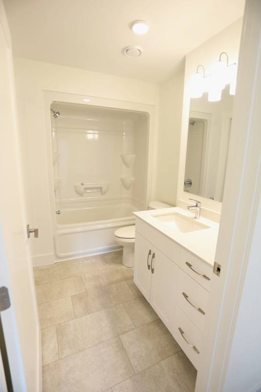 A white bathroom with a toilet, sink, and shower.