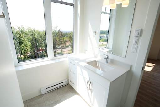 A white bathroom with a window overlooking a green landscape.