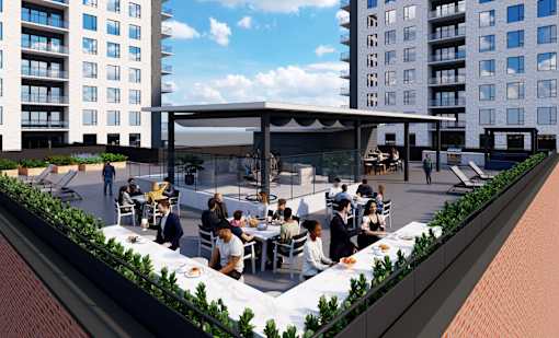 A group of people are sitting at tables under a large canopy on a rooftop.