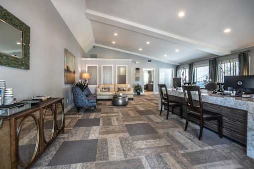 A modern kitchen with a large island and a dining area with a grey carpet.