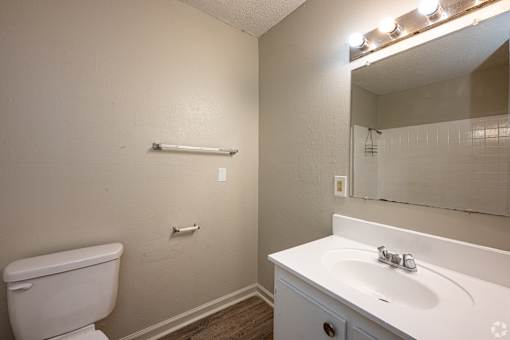 A white toilet sits next to a white sink in a small bathroom.