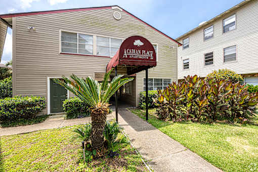 The image shows the front of the Canadian Plait Apartments building with a red awning and a palm tree in the foreground.