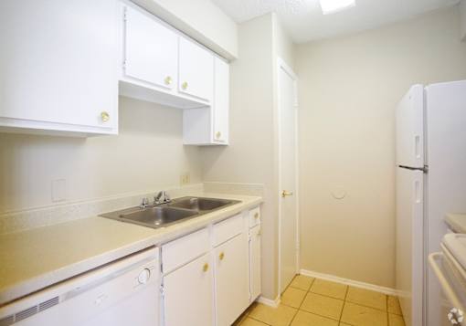 A kitchen with white cabinets and a white refrigerator.