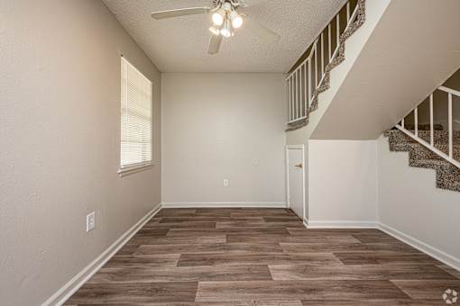 A room with a staircase and a ceiling fan.
