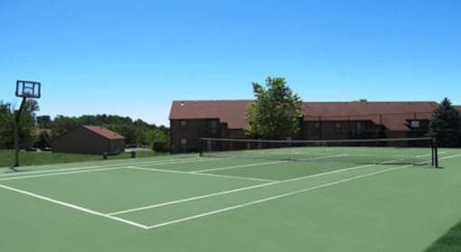 A tennis court with a basketball hoop on the side.