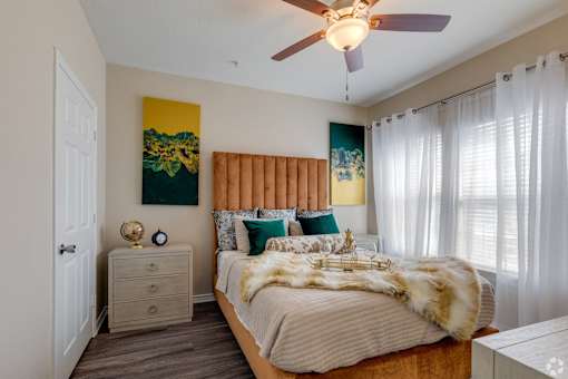A bedroom with a bed, nightstand, and a ceiling fan.