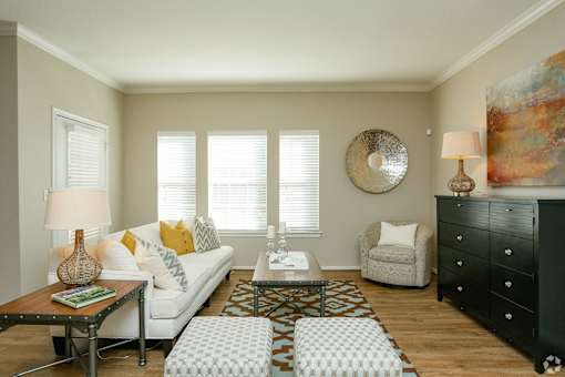 A living room with a white couch, a coffee table, and a large painting on the wall.